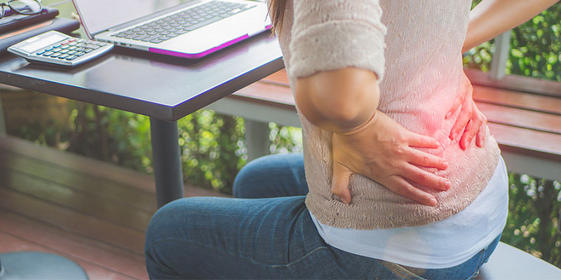 Woman sitting at a table with low back pain in Gresham OR