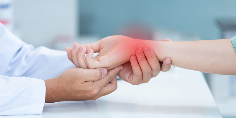 Doctor holding a woman's hand and wrist examining her carpal tunnel in Gresham OR
