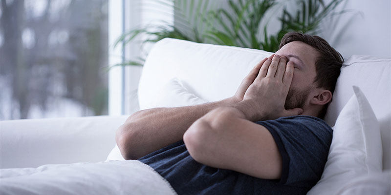 Man in bed holding his face in frustration suffering from fibromyalgia in Gresham OR