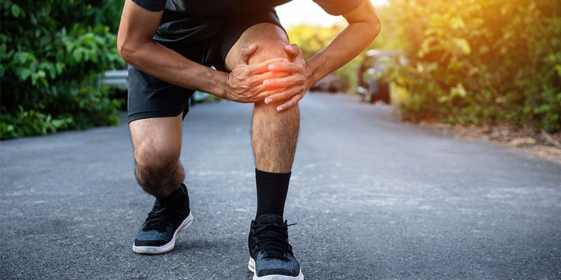 Man outdoors bending over with knee pain in Gresham OR