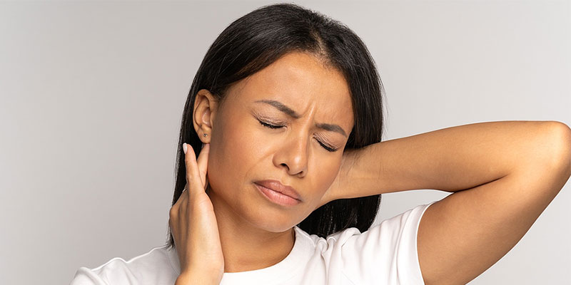 Woman wincing in pain with a pinched nerve in her neck in Gresham OR
